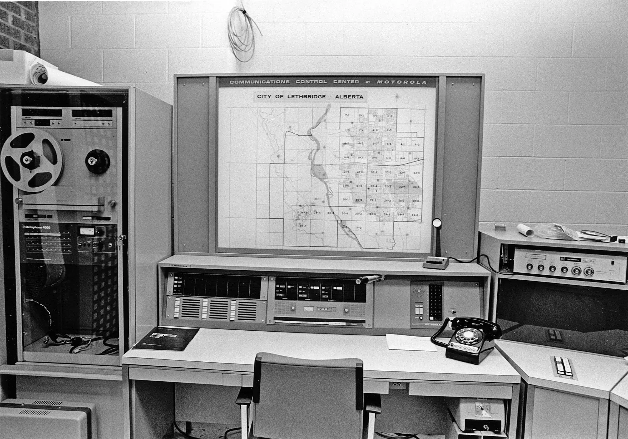 Archival Lethbridge communications console with a city map, telephone and recording equipment.