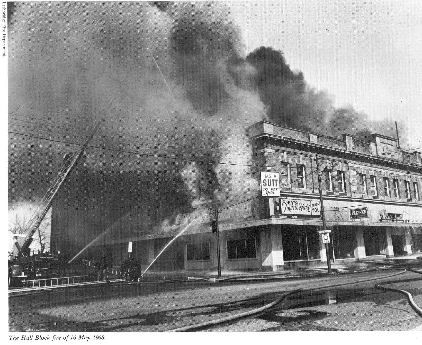 Firefighting streams directed at the smoke-filled Hull Block, with the original scan caption and credit preserved.