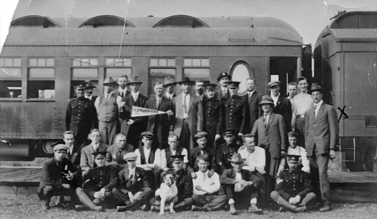The first group of wartime volunteers from Lethbridge, with Fire Chief William Hardy and fire department members, beside a train in 1914
